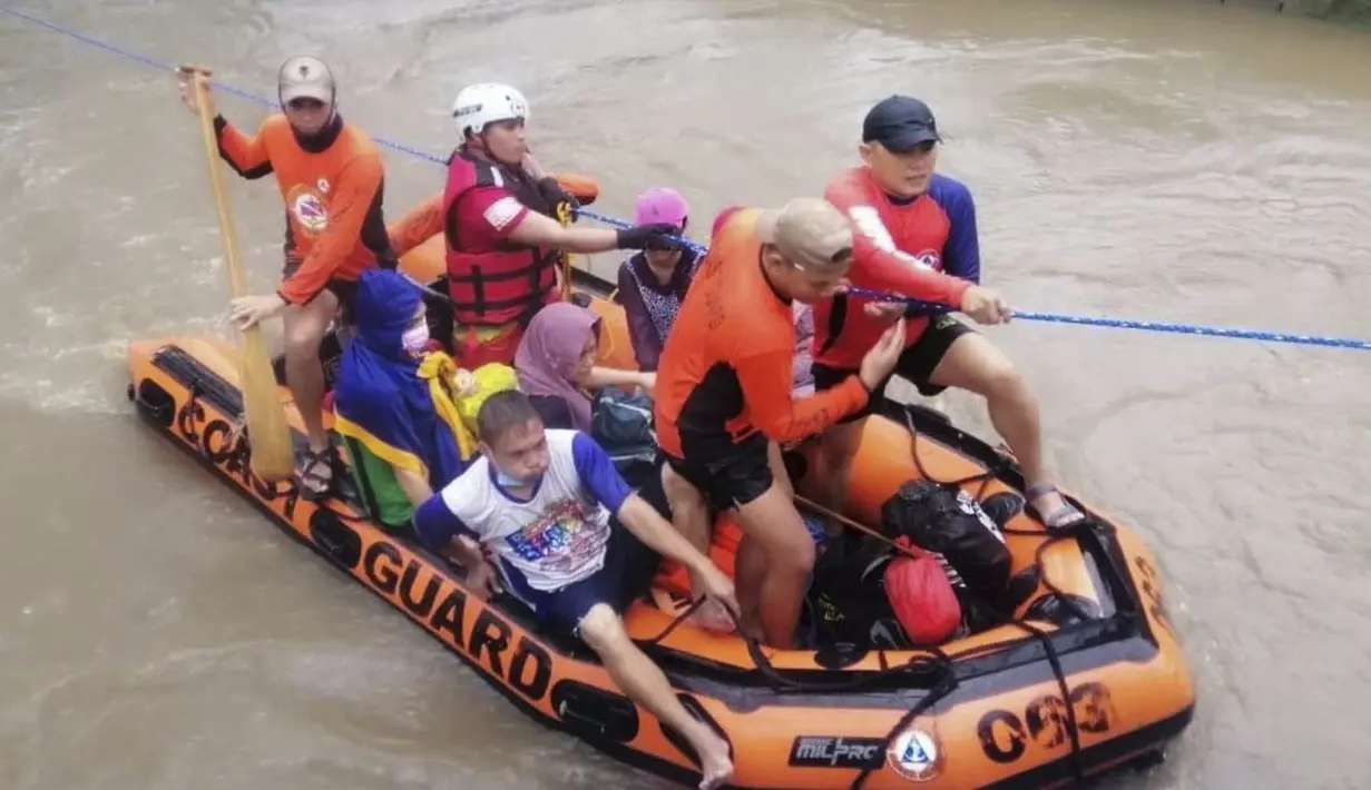 Warga menaiki perahu karet di sepanjang banjir yang disebabkan oleh Topan Rai saat mereka dievakuasi ke tempat yang lebih tinggi di Cagayan de Oro City, Filipina selatan, Kamis (16/12/2021). (Philippine Coast Guard via AP)