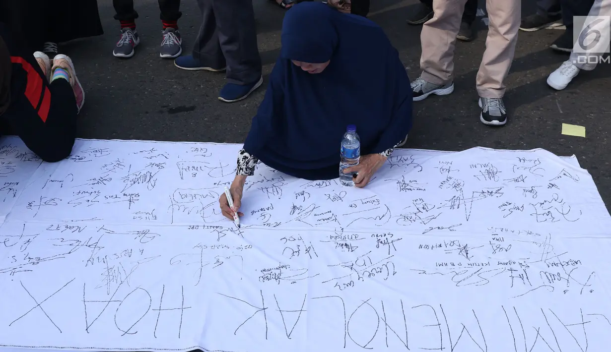 Warga menandatangani spanduk dukungan anti hoax di kawasan Bundaran Hotel Indonesia, Jakarta, Minggu (18/11). PB HMI mensosialisasikan Hoax sebagai ancaman demokrasi di Indonesia. (Liputan6.com/Helmi Fithriansyah)