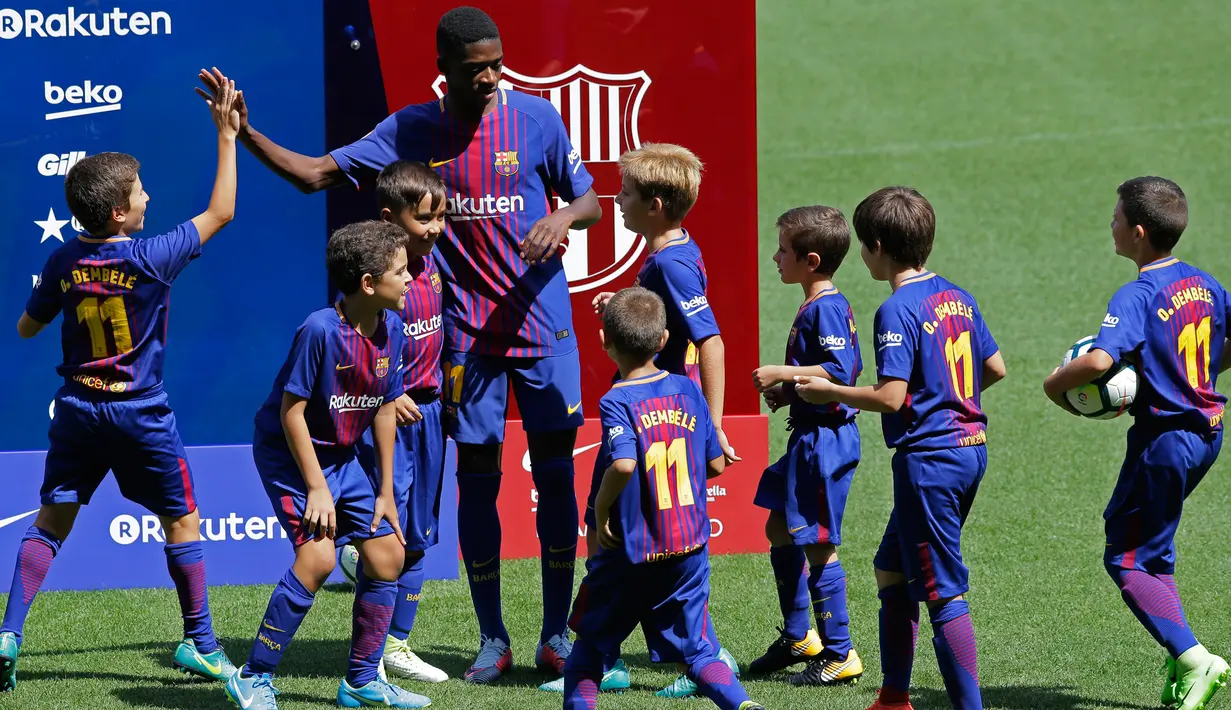 Penyerang baru Barcelona, Ousmane Dembele menyapa anak-anak saat perkenalan dirinya di Stadion Camp Nou, Barcelona, Spanyol, (28/8). Pemain asal Prancis ini dikontrak Barcelona sekitar 147 juta euro. (AP Photo / Manu Fernandez)