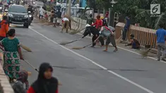 Warga berebut uang yang dilemparkan pengguna jalan menggunakan sapu di Jembatan Sewo, Indramayu, Jawa Barat, Senin (3/6/2019). Kehadiran pencari sedekah tersebut biasanya kian bertambah banyak saat menjelang arus mudik Lebaran. (Liputan6.com/Herman Zakharia)
