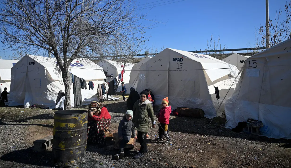 Beberapa anak-anak bermain di sebuah kamp pengungsi Suriah yang didirikan oleh lembaga bantuan Turki AFAD di distrik Islahiye, Gaziantep, Turki, Rabu (15/2/2023). Hingga kini, tim penyelamat terus berjuang melawan waktu untuk menyelamatkan korban yang masih tertimbun reruntuhan. (OZAN KOSE/AFP)