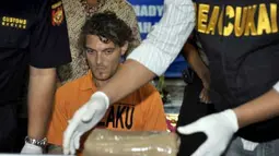 Petugas Bea Cukai memeriksa barang bukti hashis di hadapan tersangka warga Italia, Daniele Pieretto (tengah) saat gelar kasus penyelundupan narkoba di Kantor Bea Cukai Bandara Ngurah Rai, Bali, Sabtu (31/3). Tersangka berupaya menyelundupkan 1,430 Kg hashis dengan menyembunyikannya di dinding tas bawaannya. (Antara)