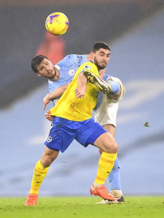 Pemain Manchester City Ruben Dias (kiri) berebut bola dengan pemain Brighton and Hove Albion Neal Maupay pada pertandingan Liga Inggris di Etihad Stadium, Manchester, Inggris, Rabu (13/1/2021). Manchester City menang 1.0. (Laurence Griffiths, Pool via AP)