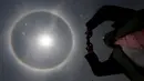 Seorang pria mengambil gambar 'Halo Matahari' di langit Mexico City, Meksiko, Kamis (21/5/2015). Menurut ahli meteorologi, fenomena cuaca menciptakan pelangi mengelilingi matahari dan dibentuk oleh refleksi dari kristal es. (REUTERS/Edgard Garrido)