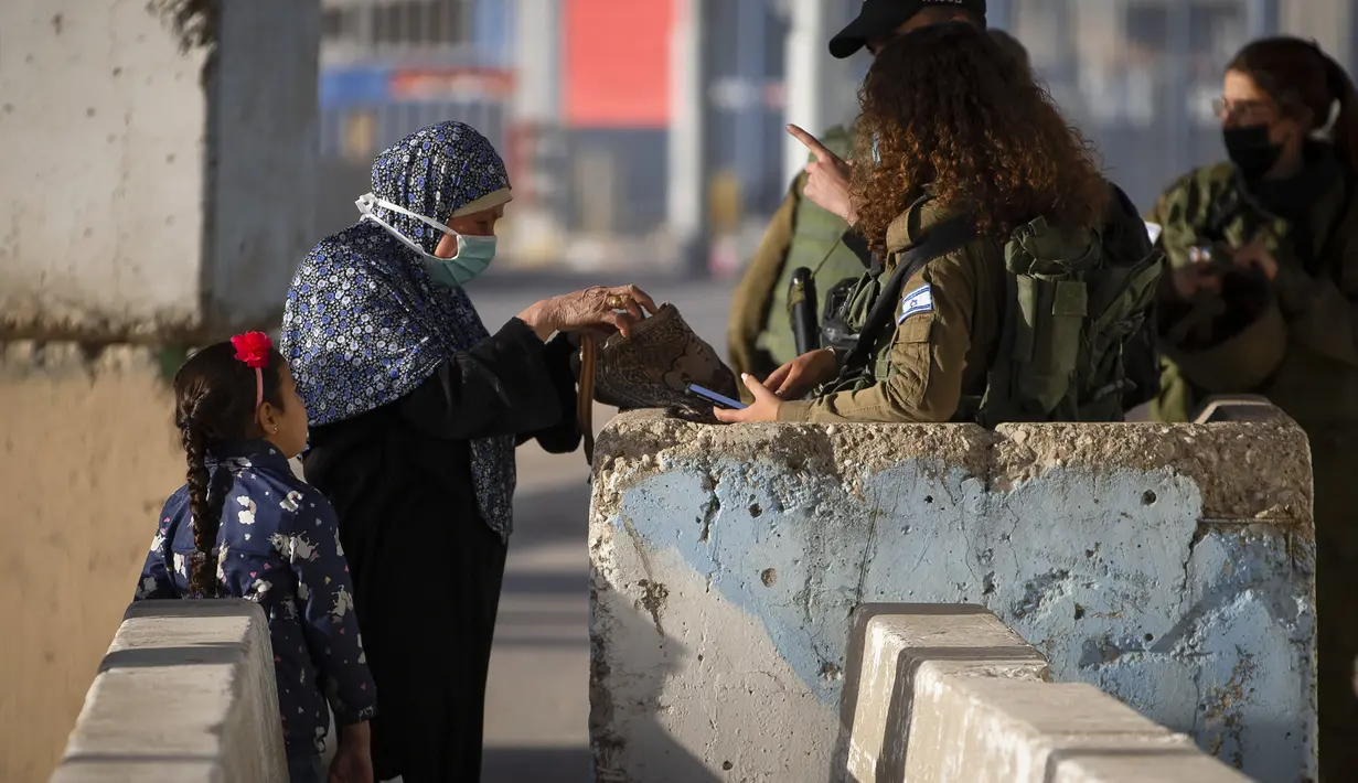 Pasukan Israel menolak mengizinkan seorang perempuan Palestina menyeberangi pos pemeriksaan Qalandia antara kota Ramallah Tepi Barat dan Yerusalem, untuk menghadiri sholat Jumat kedua bulan Ramadhan, karena mereka tidak membawa dokumen vaksinasi COVID-19, Jumat (23/4/2021). (AP Photo/Majdi Mohammed)