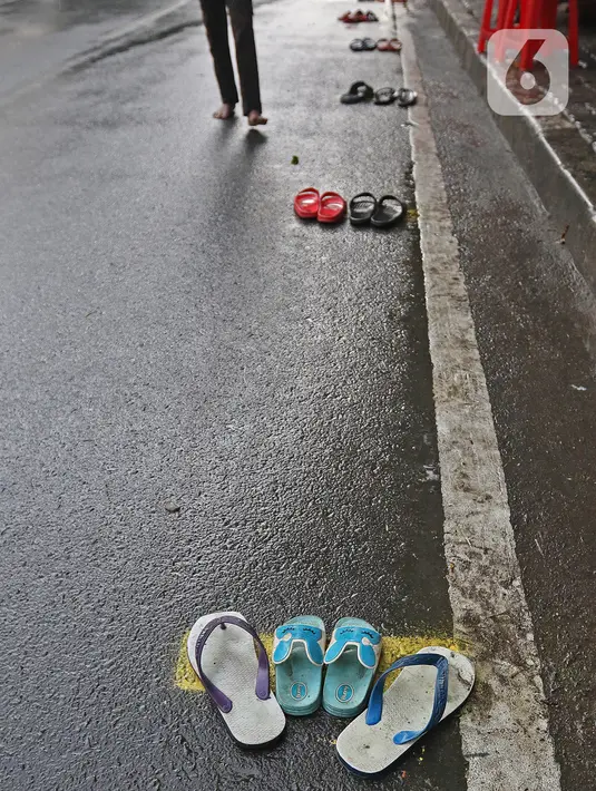 Sandal-sandal warga terlihat saat mengantre untuk mendapatkan takjil gratis di Jalan Cempaka Putih Tengah XXI, Jakarta, Rabu (14/4/2021). Pembagian takjil gratis ini dilakukan dengan menerapkan protokol kesehatan ketat. (Liputan6.com/Herman Zakharia)