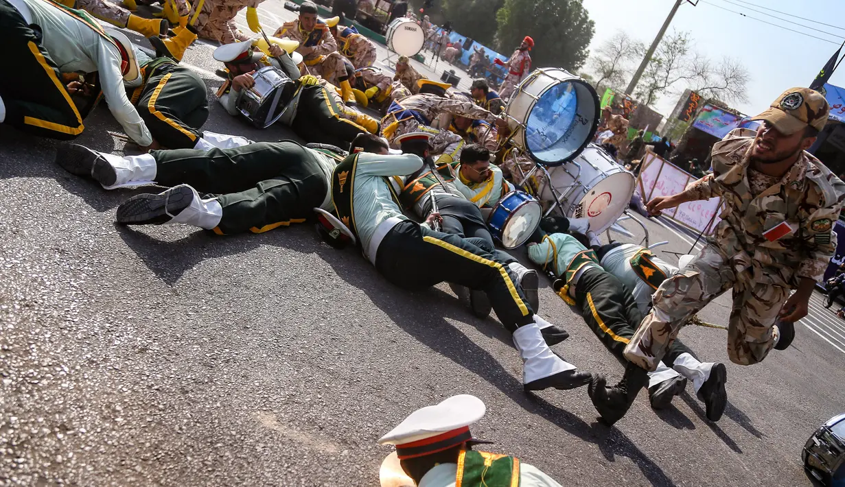 Seorang tentara berlari melewati rekannya yang tergeletak saat serangan pada parade militer di Ahvaz, Iran, Sabtu (22/9). Para pemimpin Iran menuduh negara-negara Teluk yang didukung Amerika Serikat berada di belakang serangan. (MORTEZA JABERIAN/ISNA/AFP)