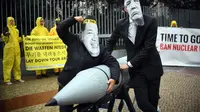 Dua aktivis berpose dengan rudal tiruan dengan memakai topeng Presiden AS, Donald Trump dan Pemimpin Korut, Kim Jon-un di Kedubes Korea Utara di Berlin, Jerman (13/9). Mereka menutut penghapusan senjata nuklir. (AFP Photo/dpa/Britta Pedersen/Germany Out)