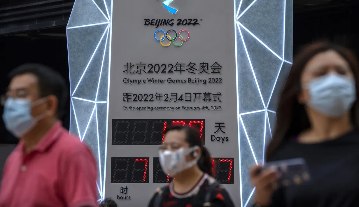 Seorang pria yang memakai masker untuk melindungi diri dari COVID-19 berjalan melewati layar yang menunjukkan jam hitung mundur ke Olimpiade Musim Dingin 2022 di Beijing (18/8/2021).  Pejabat tinggi Beijing menegaskan kembali perlunya anti-pencegahan yang ketat. (AP Photo/Mark Schiefelbein)