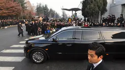 Mobil yang membawa jenazah Jonghyun SHINee keluar dari rumah persemayaman di Asan Hospital, Seoul menuju tempat pemakaman, Kamis (21/12). Ratuhan fans ikut mengantar pelepasan jenazah Jonghyun SHINee dengan isakan tangis. (JUNG Yeon-Je/AFP)