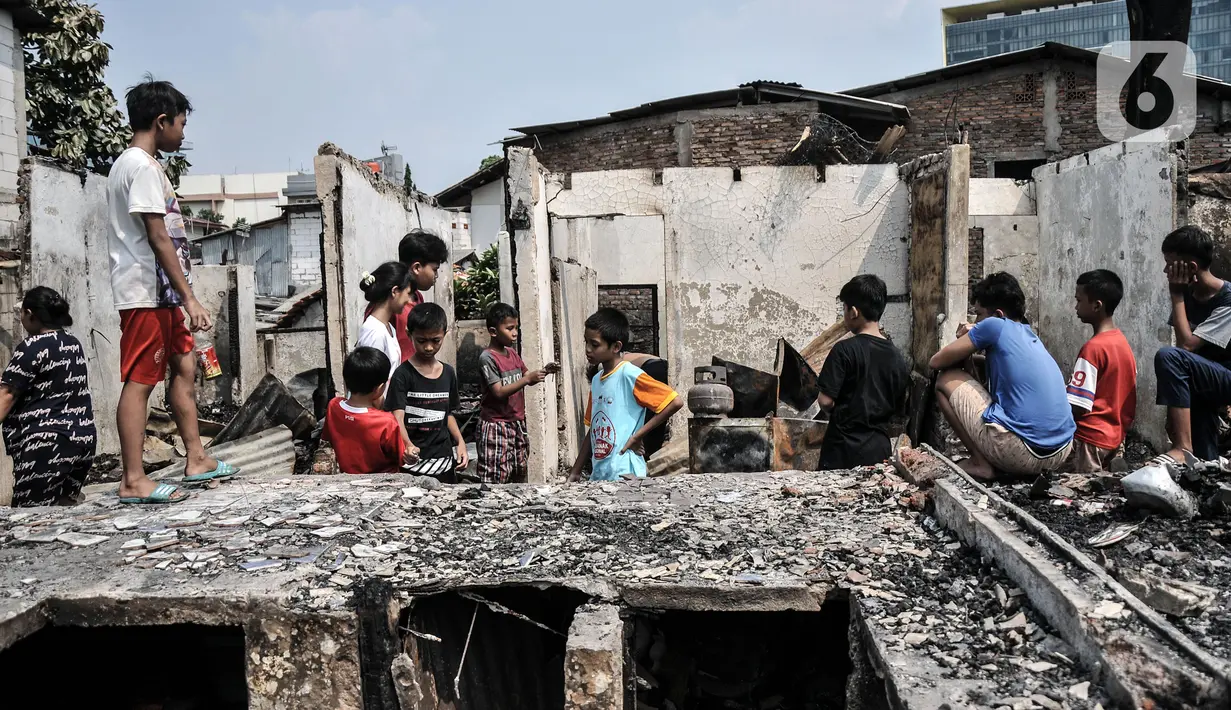 Anak-anak menyaksikan kondisi rumah pasca kebakaran melanda permukiman padat penduduk di Jalan Cikini Kramat, RT 004 dan 015, RW 001, Kelurahan Pegangsaan, Kecamatan Menteng, Jakarta Pusat, Selasa (27/9/2022). Kebakaran yang terjadi sekitar pukul 04.35 tadi diduga berasal dari ledakan kompor gas pedagang bubur yang menyebabkan satu orang mengalami luka bakar dan puluhan rumah yang dihuni 75 kepala kepala keluarga ludes dilalap api. (merdeka.com/Iqbal S Nugroho)