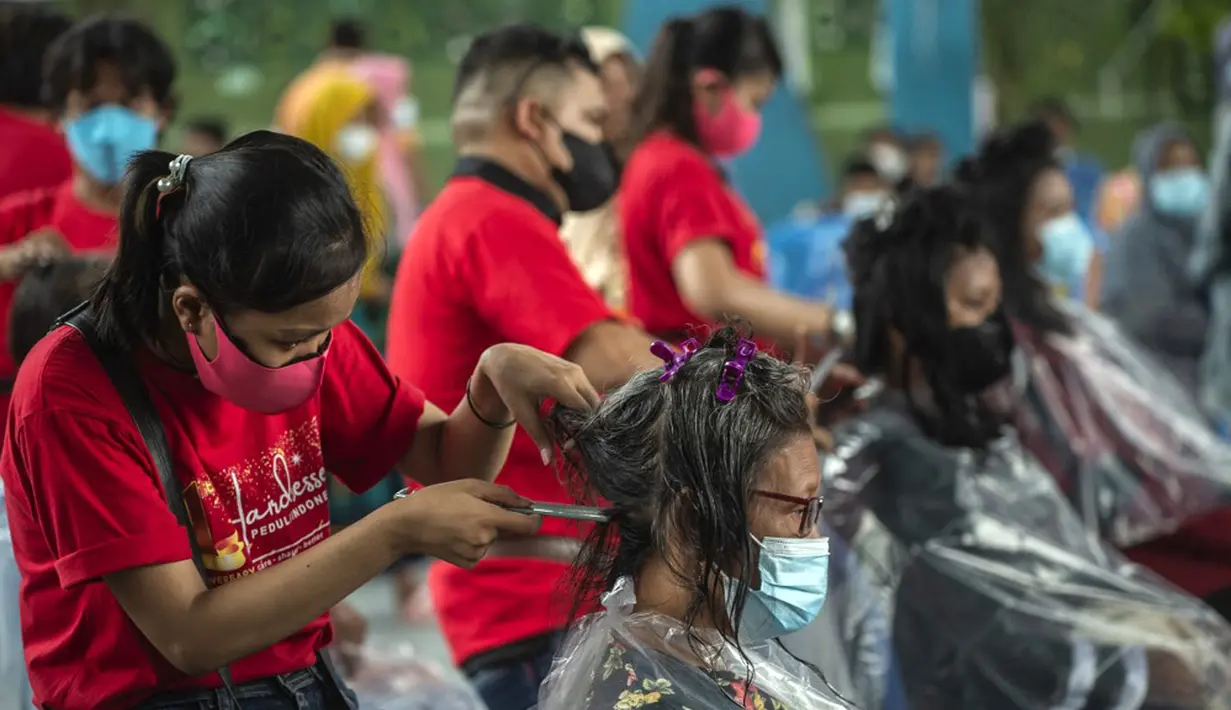 Penata rambut melakukan cukur rambut gratis saat acara amal di Surabaya, Jawa Timur, Senin (8/11/2021). Layanan cukur rambut gratis ini dilakukan kepada 100 anak yatim piatu. (Juni Kriswanto/AFP)