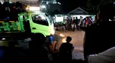 Truk melintas di tengah-tengah warga yang sedang asik nobar Timnas Indonesia U-23 vs Uzbekistan di kampung Sampora, Cisauk, Tangerang, Selasa (29/4/2024). (Bola.com/M Iqbal Ichsan)