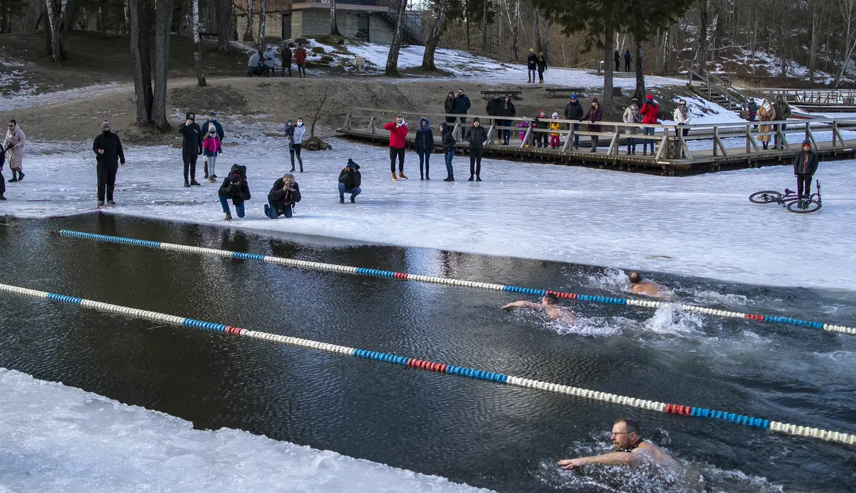 Para perenang bertanding saat kompetisi renang musim dingin di lubang es sepanjang 25 meter di sebuah danau dekat Vilnius, Lithuania, Sabtu (6/3/2021).  Suhu air saat itu 3 derajat Celcius, sedangkan udaranya -3 derajat Celsius. (AP Photo/Mindaugas Kulbis)