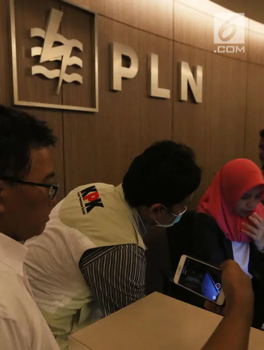 Penyidik KPK berbincang dengan salah seorang pegawai saat menggeledah Kantor Pusat PLN, Jakarta, Senin (16/7). Penyidik KPK menuju Lantai 8 yang merupakan lantai direksi PLN. (Liputan6.com/Arya Manggala)