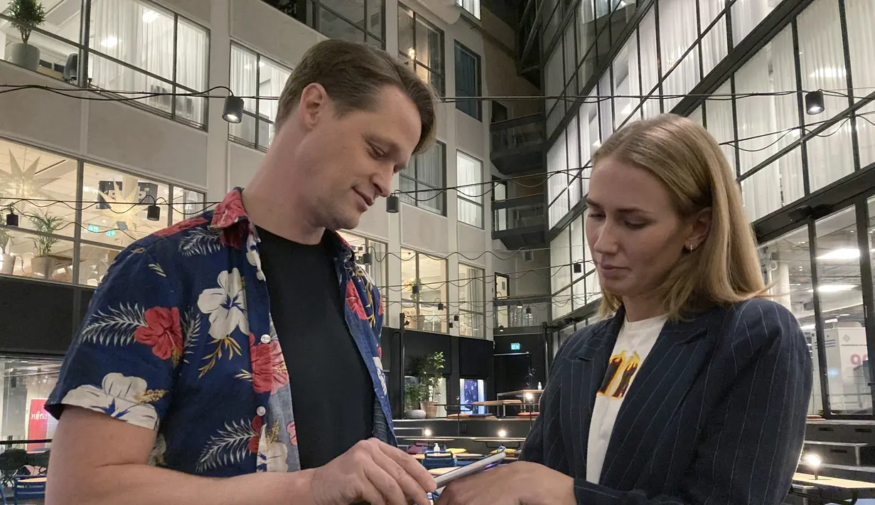 Direktur DSruptive Subdermals, Hannes Sjoblad memindai implan di tangan manajer pemasaran, Amanda Back dengan smartphone untuk mengungkapkan kartu kesehatannya di Epicenter Stockholm (20/12/2021). (AFP/Viken Kantarci)