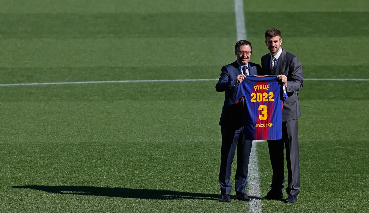 Bek Spanyol, Gerard Pique dan Presiden Barcelona, Josep Maria  berpose memegang jersey Barcelona pada pengumuman perpanjangan kontraknya di stadion Camp Nou, Senin (29/1). Bek timnas Spanyol itu meneken kontrak baru hingga 30 Juni 2022 (AP/Manu Fernandez)