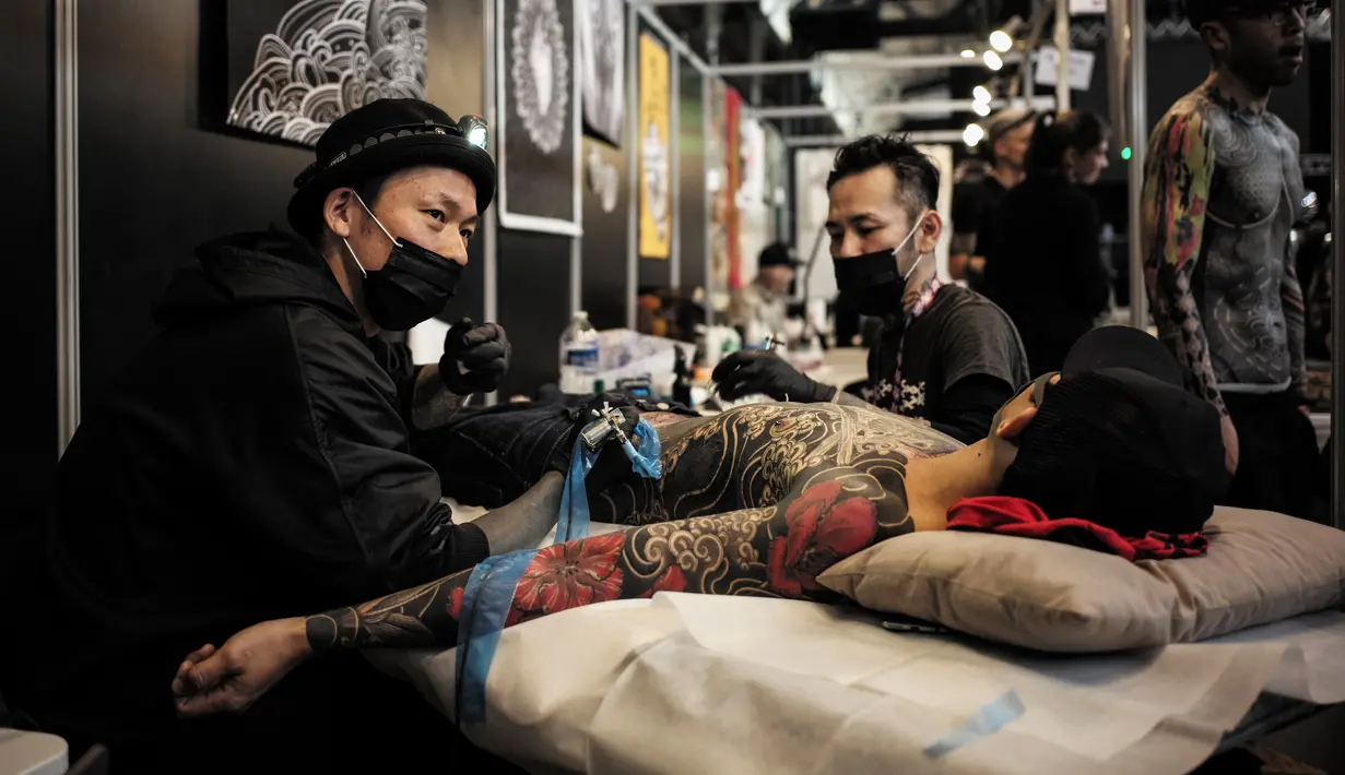 Seorang pria berbaring saat tubuhnya di tato dalam acara Konvensi Tattoo Paris (Mondial du Tatouage) di Grand Halle de la Villette di Paris (8/3). Acara ini menjadi ajang berkumpulnya bagi para penyuka, penggemar dan seniman tato. (AFP/Philippe Lopez)