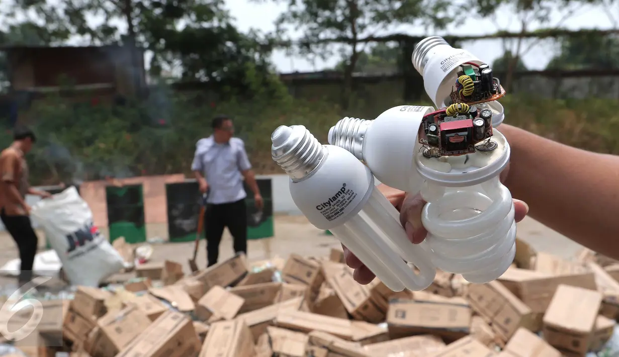 Petugas memperlihatkan lampu hemat energi tak ber-SNI yang siap dibakar oleh petugas di halaman Kemendag, Jakarta, Kamis (29/10). Dirjen SPK Kemendag juga memusnahkan 79 unit pompa air listrik asal China yang tak ber-SNI. (Liputan6.com/Angga Yuniar)