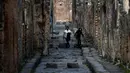 Wisatawan berjalan di gang berbatu, Pompeii, Italia, Senin (25/11/2019). Sisa-sisa kehidupan di Kota Pompeii masih tetap bertahan hingga sekarang. (Filippo MONTEFORTE/AFP)