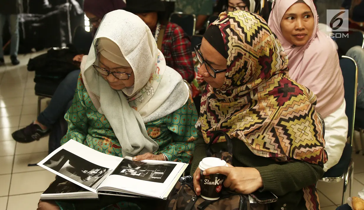 Bunda Ifet melihat buku "Tanpa Batas" fotografer Tjandra Moh Amin, Jakarta (14/12). Tjandra mencoba menerjemahkan kehidupan Slank secara utuh, menguak sisi humanisme personil  Slank yang jarang tersentuh media tanah air. (Liputan6.com/Herman Zakharia)