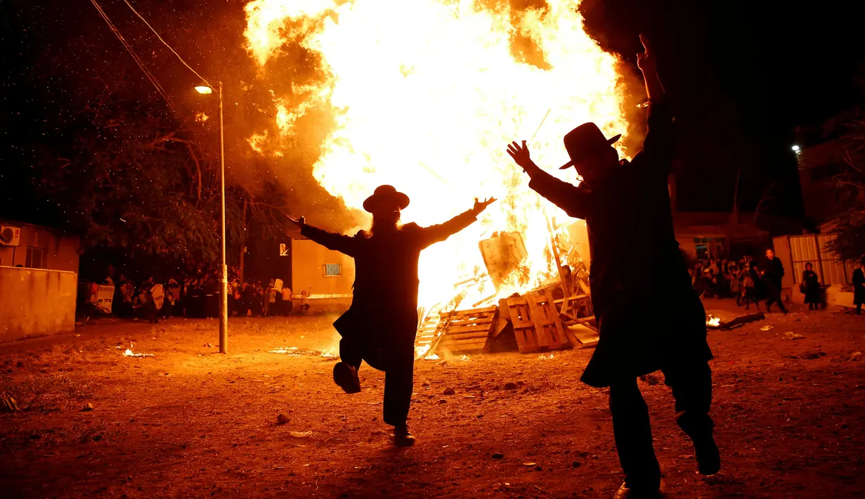 Dua orang Yahudi Ultra-Ortodoks menari di samping api unggun selama perayaan hari libur Yahudi Lag Ba-Omer di Shearim, Yerusalem, (25/5). Hari libur Yahudi ini terjadi pada hari ke-18 dari bulan Ibrani dari Iyar. (REUTERS/Ronen Zvulun)