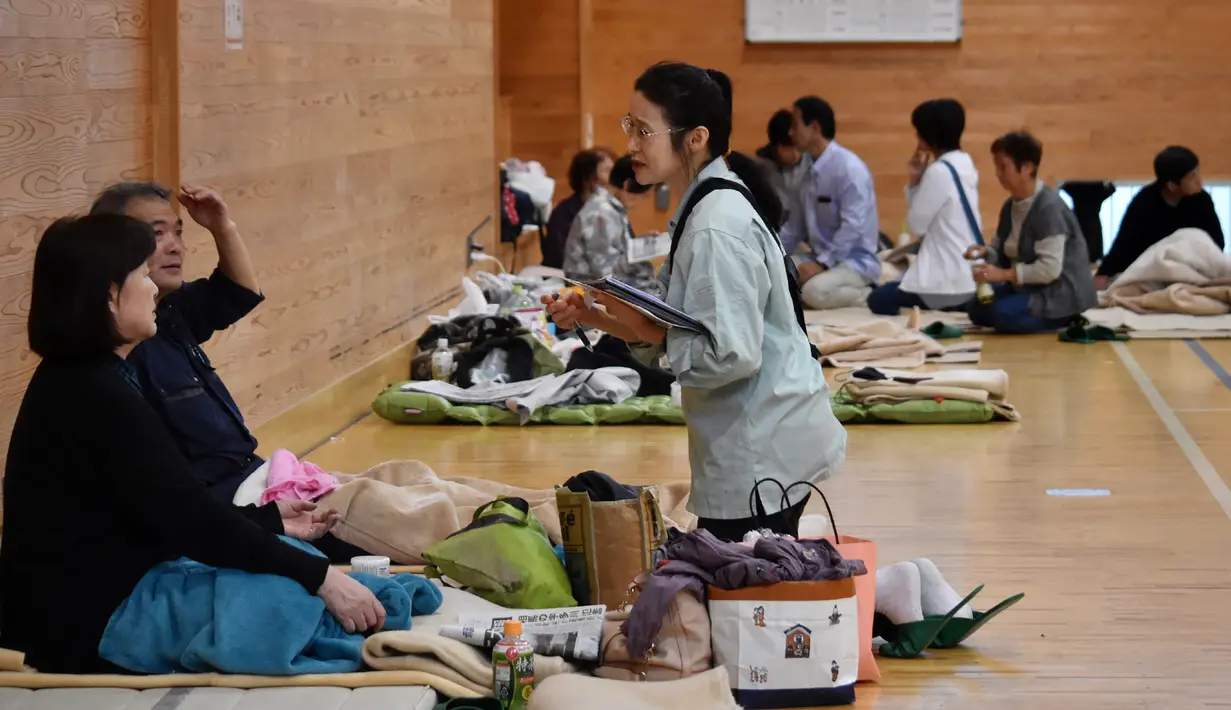 Pejabat kota Koriyama memeriksa kesehatan penduduk yang dievakuasi di tempat penampungan di dalam sebuah sekolah dasar di Koriyama, prefektur Fukushima (14/10/2019). Sedikitnya 43 orang tewas akibat dilandan Topan Hagibis. (AFP Photo/Jiji Press)