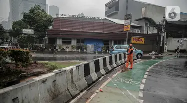 Petugas PPSU membersihkan sampah dekat beton pembatas di Jalan Senopati, Jakarta, Minggu (29/12/2019). Pascakejadian mobil tabrak Apotek Senopati, Suku Dinas Bina Marga memasangan beton pembatas untuk meminimalisir kejadian serupa terulang kembali. (Liputan6.com/Faizal Fanani)