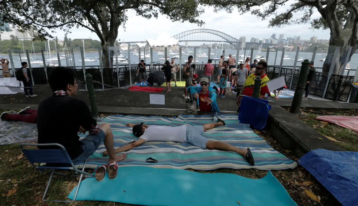 Warga sudah menempati posisi dengan menggelar tikar sambil tiduran untuk menonton kembang api jelang pergantian Tahun Baru di depan Opera House Sydney, Australia, (31/12/2016). (REUTERS/Jason Reed)
