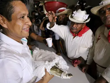 Wali Kota San Pedro Huamelula, Joel Vasque (kiri) menikahi seekor buaya di Oaxaca, Meksiko, 30 Juni 2015. Pernikahan ini bertujuan untuk mendatangkan hasil laut yang melimpah kepada penduduk nelayan di desa setempat. (AFP PHOTO/MARIO JIMENEZ)
