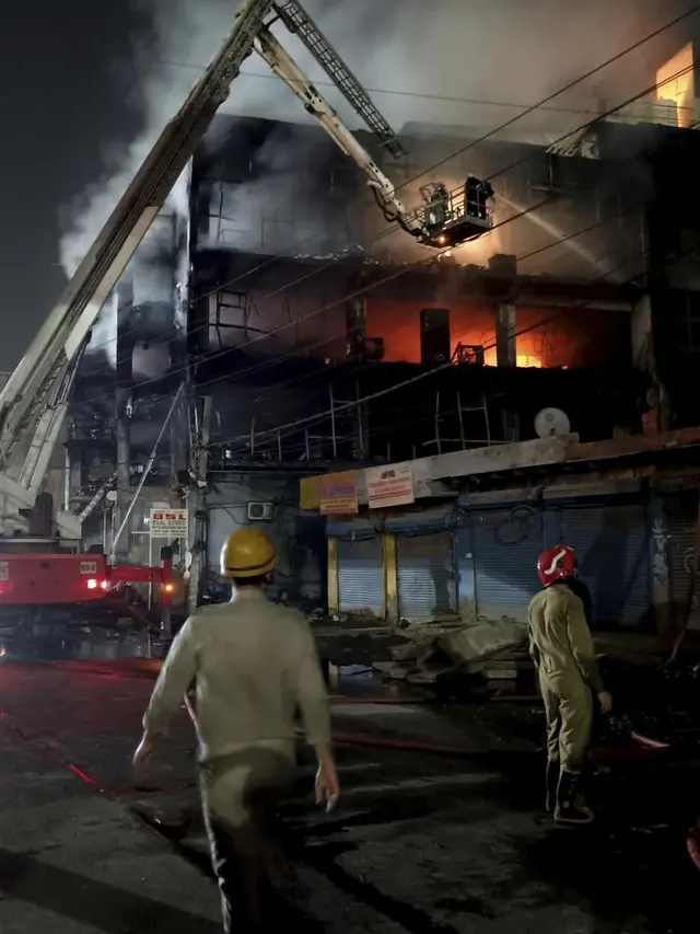 Petugas pemadam kebakaran berusaha memadamkan api di sebuah gedung berlantai empat, di New Delhi, India, Jumat, 13 Mei 2022. (Foto AP/Dinesh Joshi)