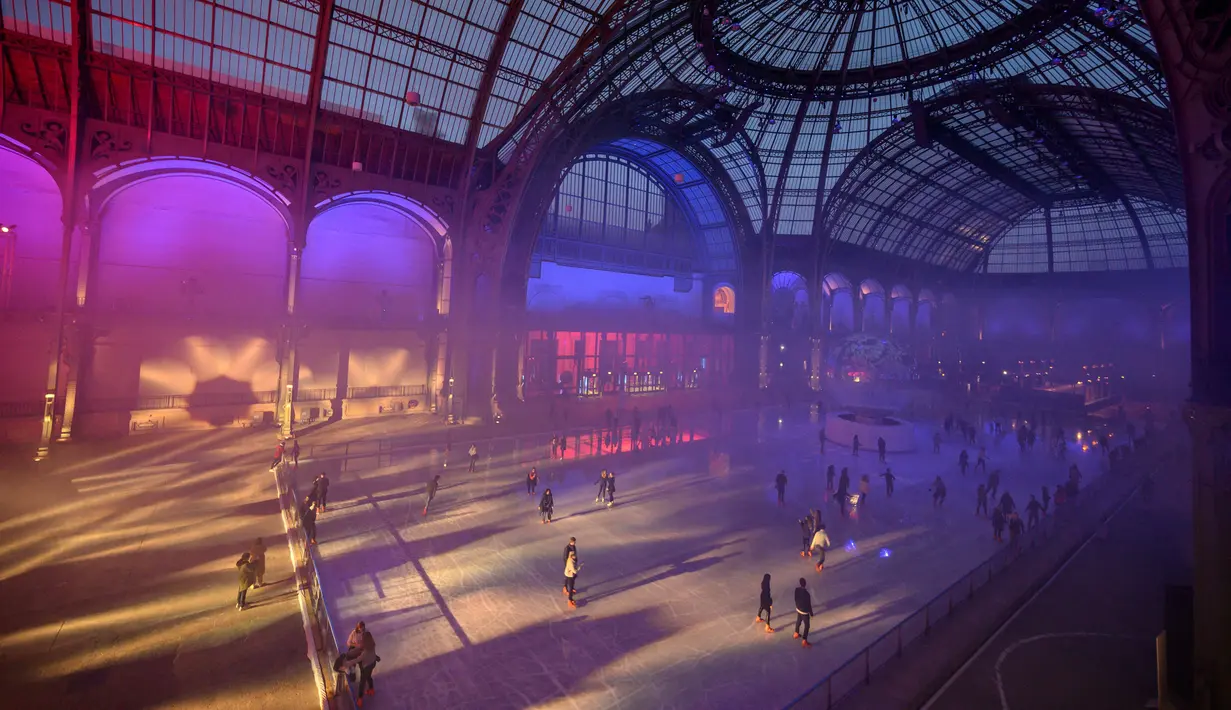 Orang-orang berseluncur di arena ice skating di bawah kubah kaca mewah legendaris, Grand Palais, Paris, Selasa (17/12/2019). Aren seluncur es musiman ini terbuka untuk umum selama liburan Natal. (Photo by Thomas SAMSON / AFP)