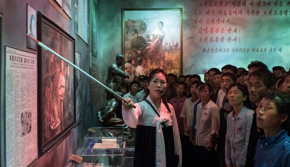 Pemandu menunjukkan lukisan di Sinchon Museum of American War Atrocities di Pyongyang 24 Juli 2017. Museum ini menampilkan kejadian pembantaian yang diduga dilakukan oleh angkatan bersenjata AS dan Korsel pada Perang Korea 1950-1953. (AFP Photo/Ed Jones)