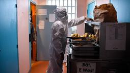 Seorang narapidana (kanan) yang mengenakan alat pelindung diri (APD) membagikan makanan siang kepada para tahanan di sel mereka sebagai bagian dari langkah-langkah mengekang penyebaran Covid-19 di pusat-pusat penahanan, di penjara Villepinte, dekat Paris, pada 6 Januari 2022. (ALAIN JOCARD/POOL/AFP)