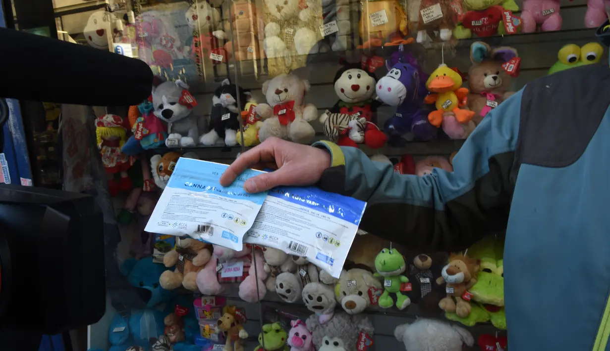 Seorang pria menunjukkan dua kemasan ganja kepada awak media yang baru dibeli di apotek di Montevideo, Uruguay (19/7). Apotek ini menjual ganja tersebut seharga USD 6,5 atau berkisar Rp 86.000 per lima gram. (AFP Photo/Miguel Rojo)