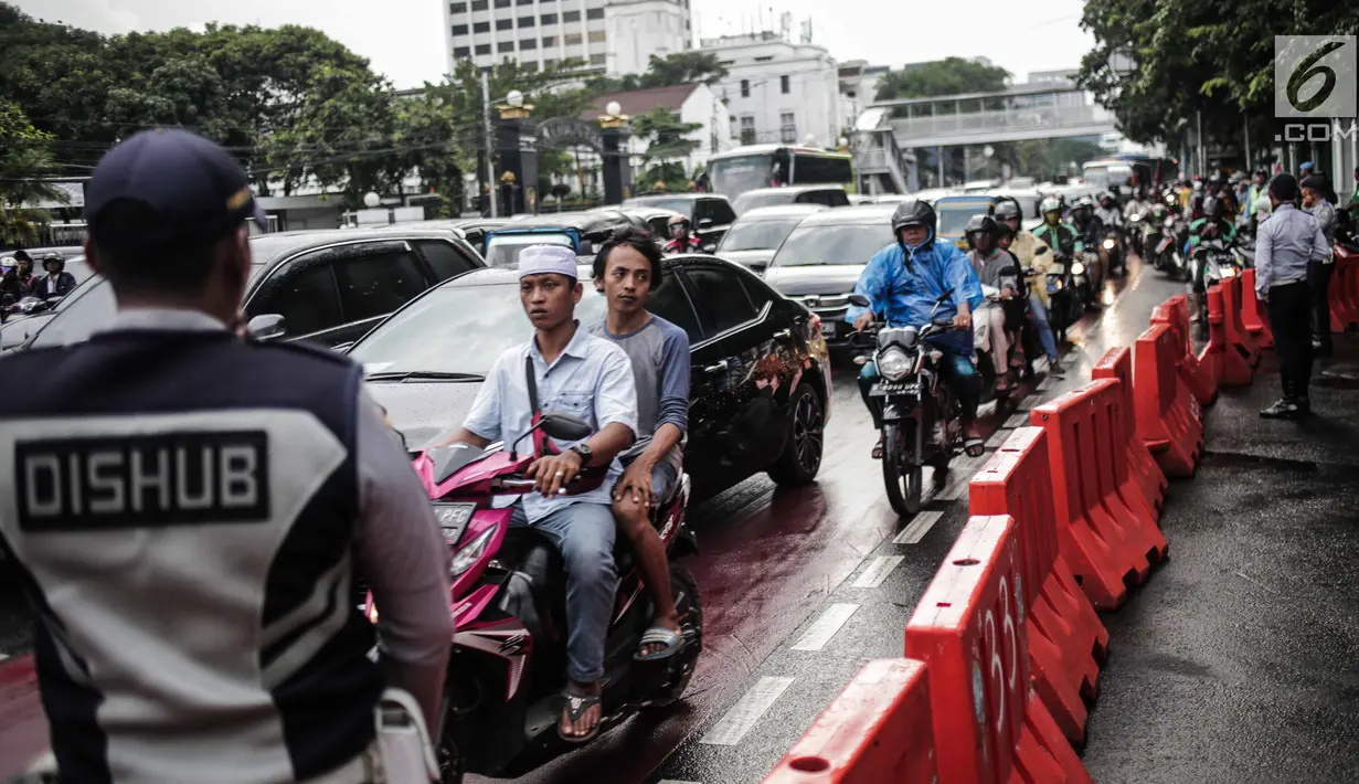 Petugas Dishub mengalihakan arus lalu lintas terkait Malam Munajat 212 di Medan Merdeka Barat dan Utara, Jakarta, Kamis (21/2). Arus lalu lintas di sekitar kawasan Monas akan ditutup untuk mencegah kemacetan. (Liputan6.com/Faizal Fanani)