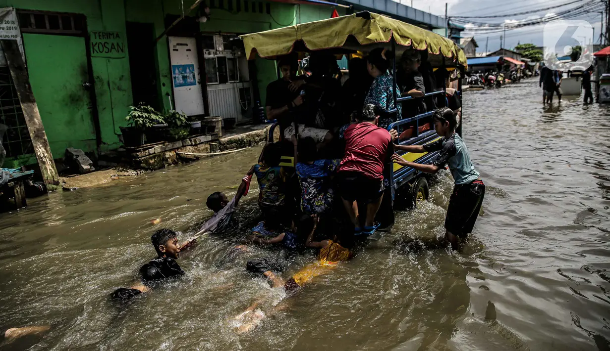 Sejumlah anak bermain air banjir rob di kawasan Muara Angke, Jakarta, Selasa (9/11/2021). Badan Penanggulangan Bencana Daerah (BPBD) DKI Jakarta memperkirakan puncak musim hujan dan potensi rob di Ibu Kota terjadi pada Januari hingga Februari 2022. (Liputan6.com/Faizal Fanani)