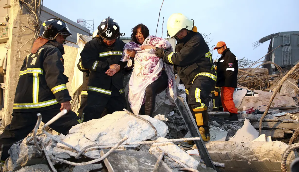 Petugas penyelamat membantu wanita di bangunan yang rusak akibat gempa 6,4 SR  di Tainan, (6/2). Gempa terjadi pukul 4 subuh tadi telah menghancurkan beberapa apartemen di kawasan Wei Guan, Tainan, Taiwan. (REUTERS/Stringer)