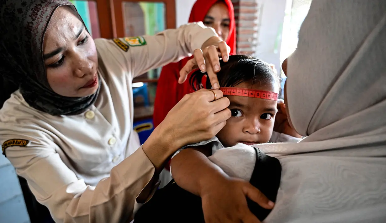 Seorang petugas kesehatan mengukur lingkar kepala bayi dalam program pemeriksaan kesehatan bulanan untuk anak-anak di sebuah pusat layanan terpadu di Banda Aceh, Senin,  10 Agustus 2026. (AFP/ Chaideer Mahyuddin)