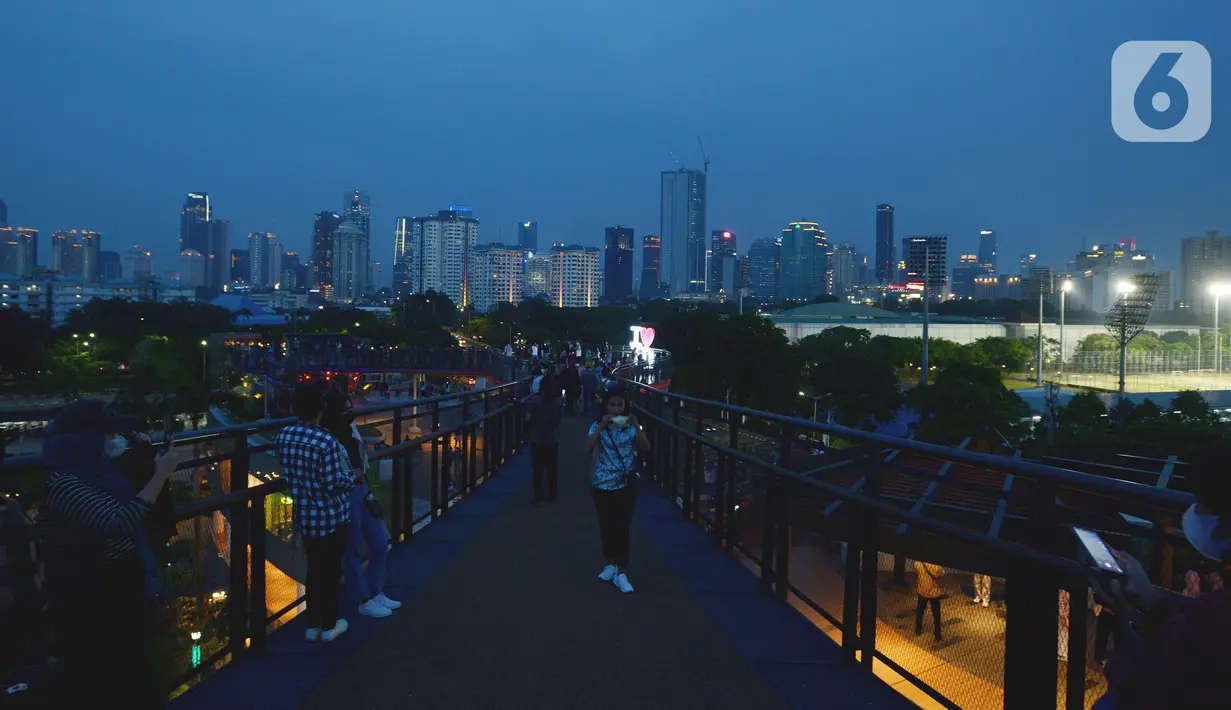 Pengunjung menikmati pemandangan dari Skywalk Senayan Park, Jakarta, Rabu (29/12/2021). Kawasan yang menyajikan pemandangan lanskap perkotaan itu menjadi alternatif destinasi wisata Jakarta yang instagramble dengan spot foto yang beragam. (merdeka.com/Imam Buhori)