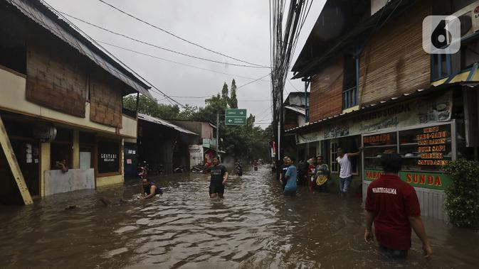 Warga beraktivitas diarea lingkungannya yang tergenang banjir di Jalan Hang Lekir, Kebayoran Lama, Jakarta Selatan, Rabu (1/1/2020). Banjir tersebut disebabkan karena tingginya intensitas hujan yang mengguyur sejak Selasa (31/12/2019). (Liputan6.com/Johan Tallo)