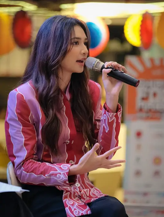 Mikha Tambayong mengombinasikan atasan batik bernuansa kemerahan dengan celana panjang hitam. Batik yang dikenakan Mikha Tambayong menarik karena menyerupai outer dengan garis leher yang unik. [Foto: Instagram/miktambayong]