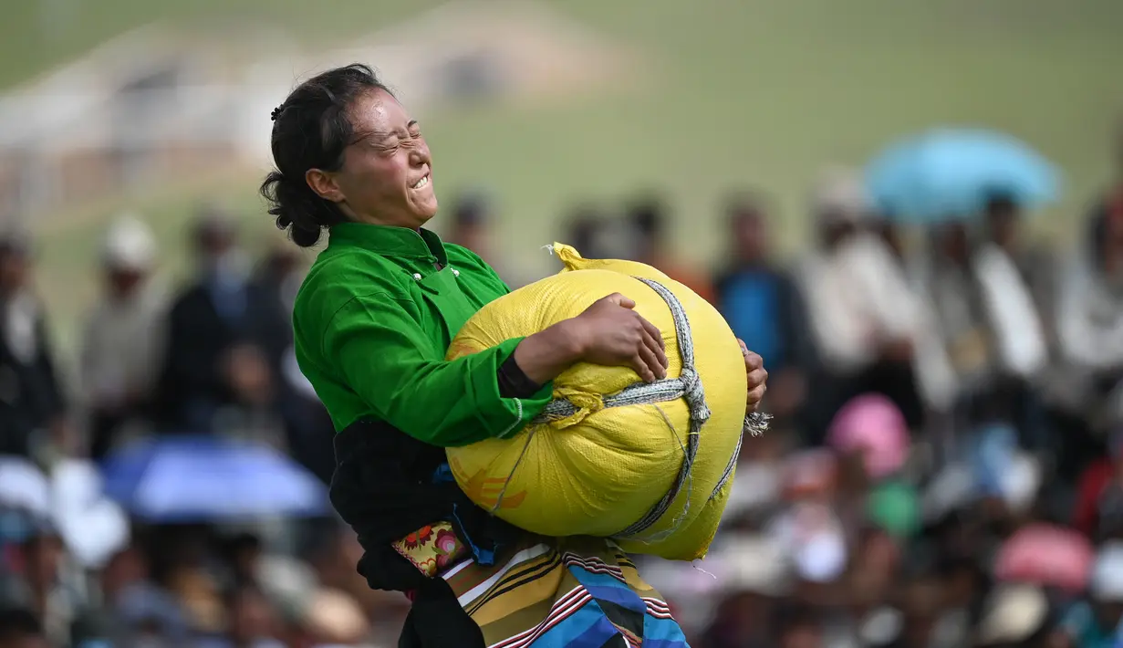 Seorang partisipan mengangkat karung berisi barli dataran tinggi dalam sebuah kompetisi yang digelar saat festival balap kuda Dangjiren di Wilayah Damxung, Daerah Otonom Tibet, China barat daya, pada 11 Agustus 2020. (Xinhua/Purbu Zhaxi)