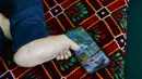 Seniman Robaba Mohammadi menggunakan ponsel dengan jari kaki di studionya di Kabul pada 5 Desember 2019. Meski terlahir dengan kaki dan tangan yang tidak bisa digunakan serta tak mendapatkan akses pendidikan, Robaba mampu membuat lukisan yang terbilang rumit dan penuh warna. (NOORULLAH SHIRZADA/AFP)