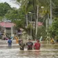 Warga mengarungi jalan yang dilanda banjir di Hulu Langat, luar Kuala Lumpur, Malaysia, Minggu  (19/12/2021). Kuala Lumpur dan perkampungan sekitarnya dilanda banjir akibat hujan deras selama dua hari, menyebabkan ribuan warga mengungsi dan banyak jalan yang memutus akses. (Foto AP/Vincent Thian)