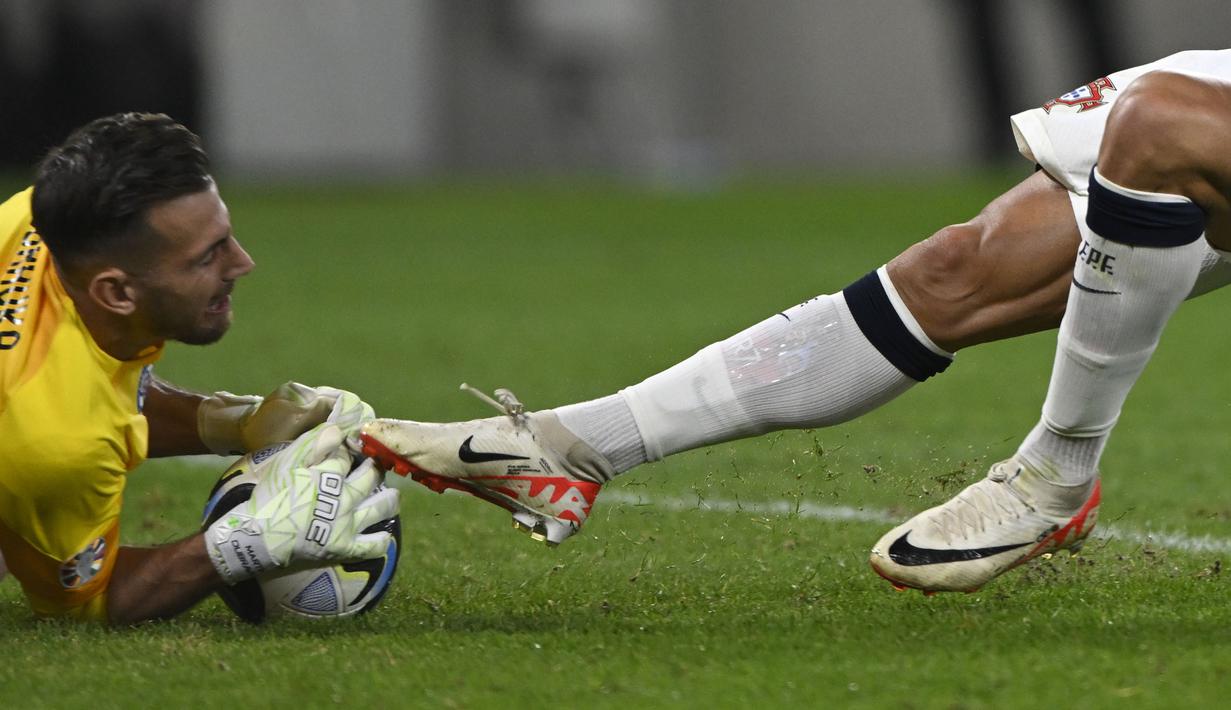 Kaki pemain Portugal, Cristiano Ronaldo (kanan) saat meluncur untuk merebut bola dari kiper Slovakia, Martin Dubravka pada laga grup G Kualifikasi Euro 2024 di National Football Stadium in Bratislava, Slovakia, Sabtu (9/9/2023) dini hari WIB. (AP Photo/Radovan Stoklasa)