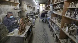 Kesibukan para tukang kayu Palestina saat membuat patung keagamaan dari kayu zaitun di sebuah toko dekat Church of the Nativity, Betlehem, Tepi Barat, 21 Desember 2020. Patung-patung tersebut akan dijual selama musim Natal. (HAZEM BADER/AFP)