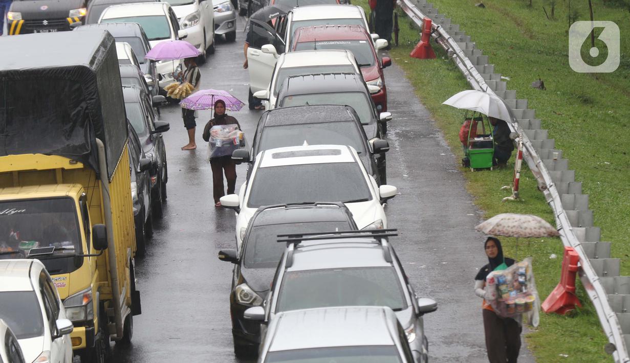 Sejumlah pedagang asongan menawarkan dagangan kepada pengendara di jalan tol Jagorawi yang sedang menanti waktu buka tutup jalur menuju kawasan wisata puncak, Bogor, Jawa Barat, Sabtu (31/10/2020). (Liputan6.com/Helmi Fithriansyah)