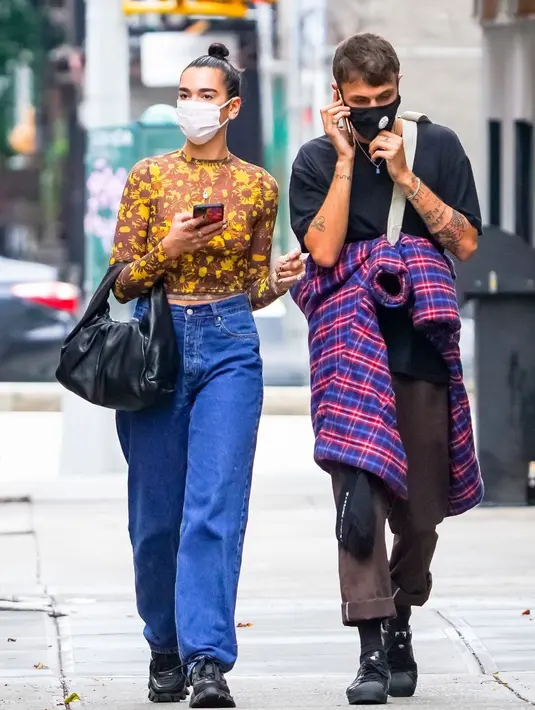 Dengan nuansa yang lebih meriah, Dua Lipa terlihat mengenakan atasan cokelat bermotif abstrak dan sentuhan warna kuning, dupadunya dengan boyfriend jeans dan sepatu hitam. Kembali menenteng Bottega Veneta Shoulder Pouch. Foto: Document/Bottega Veneta.