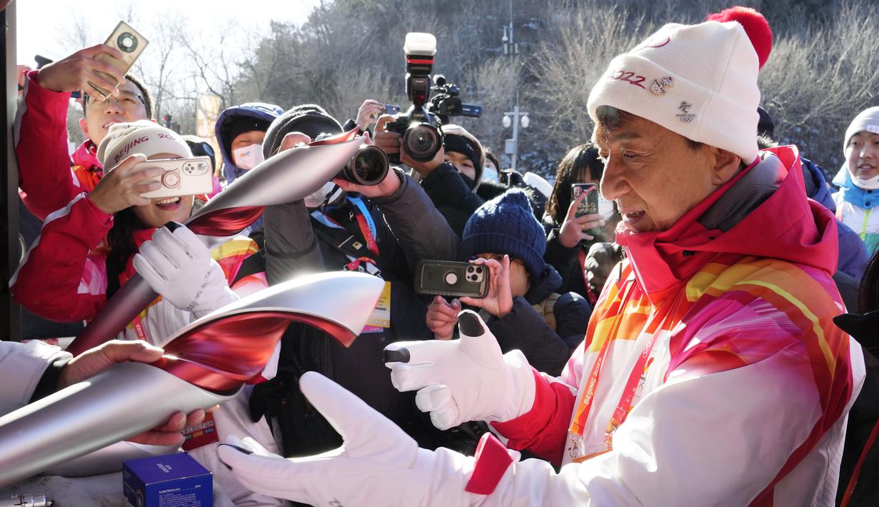 Selebriti Hong Kong Jackie Chan menerima obor Olimpiade Musim Dingin 2022 setelah mengambil bagian dalam estafet obor di Tembok Besar Badaling di pinggiran Beijing, Cina, Kamis, 3 Februari 2022. (AP/Ng Han Guan)